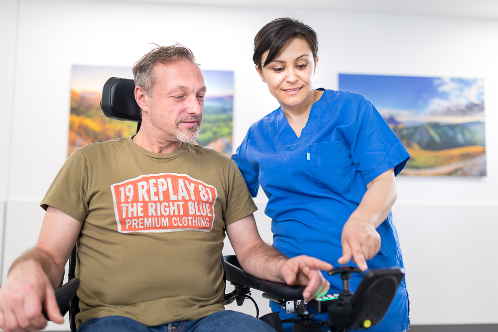 Patient im Rollstuhl mit Pflegekraft