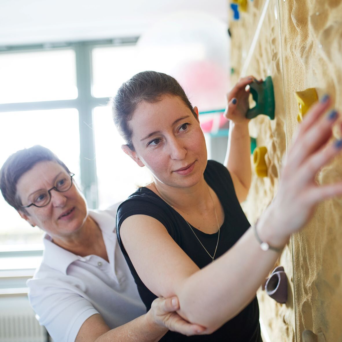 Frau mit Therapeutin an der Boulder Wand
