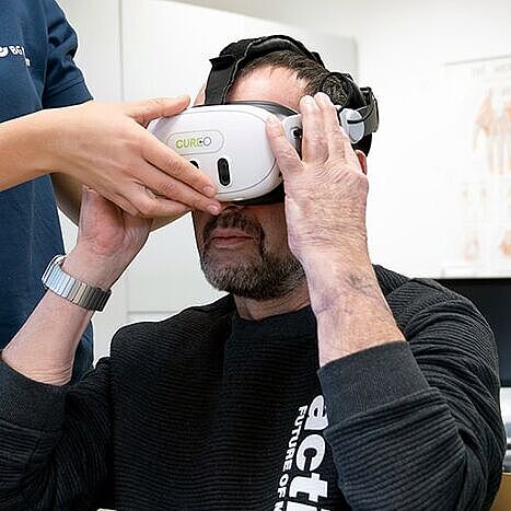 VR-Einsatz in der Therapie Therapeutin hilft beim Aufsetzen der VR-Brille