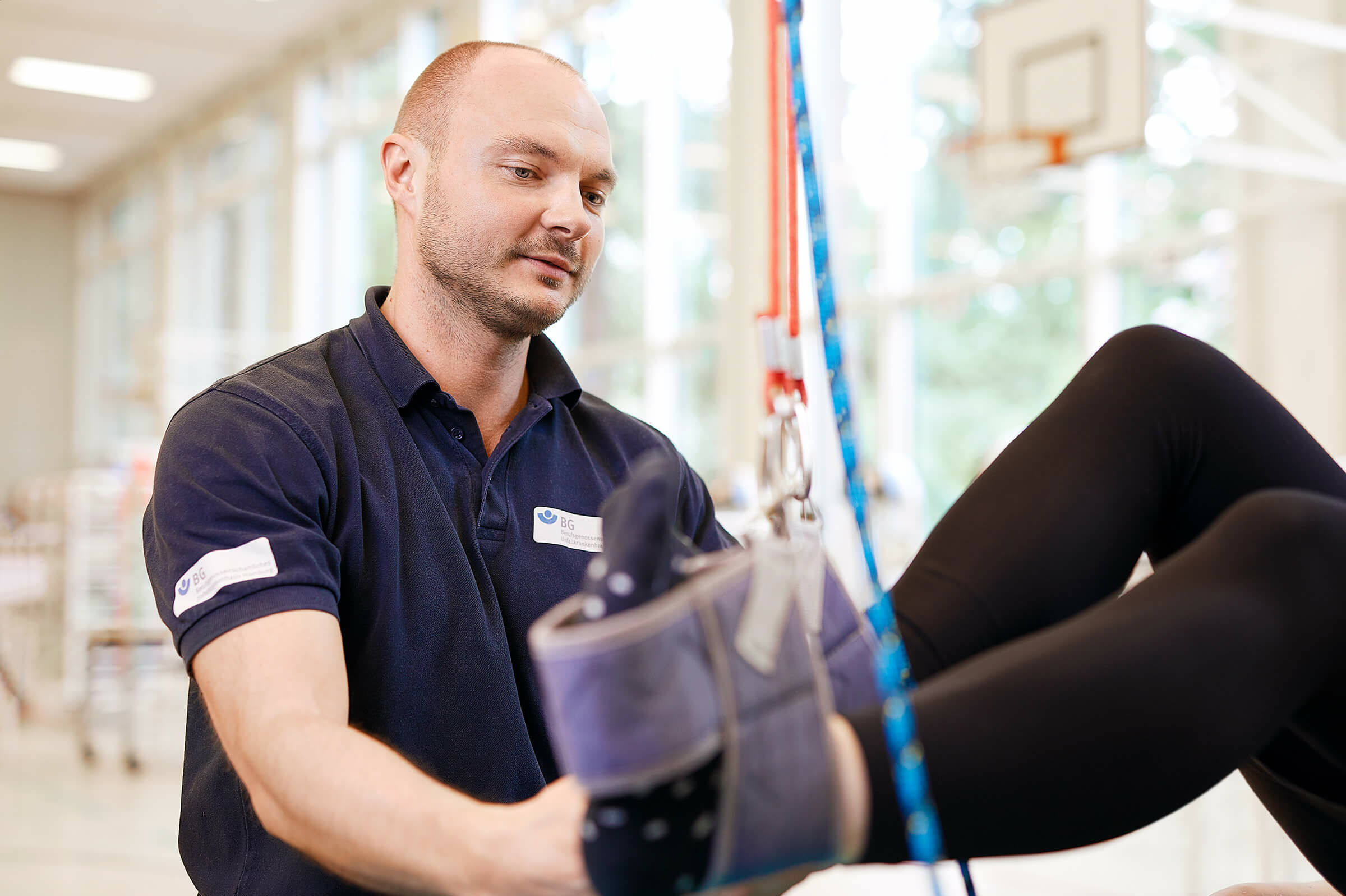 Rehatherapeut kontrolliert Klettergurte von Patientin Qualitäts- und Riskomanagement