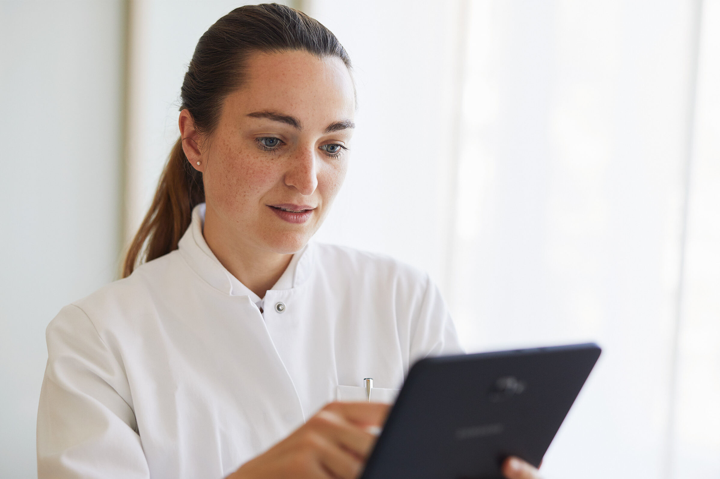 Eine junge Ärztin tippt auf einem Tablet