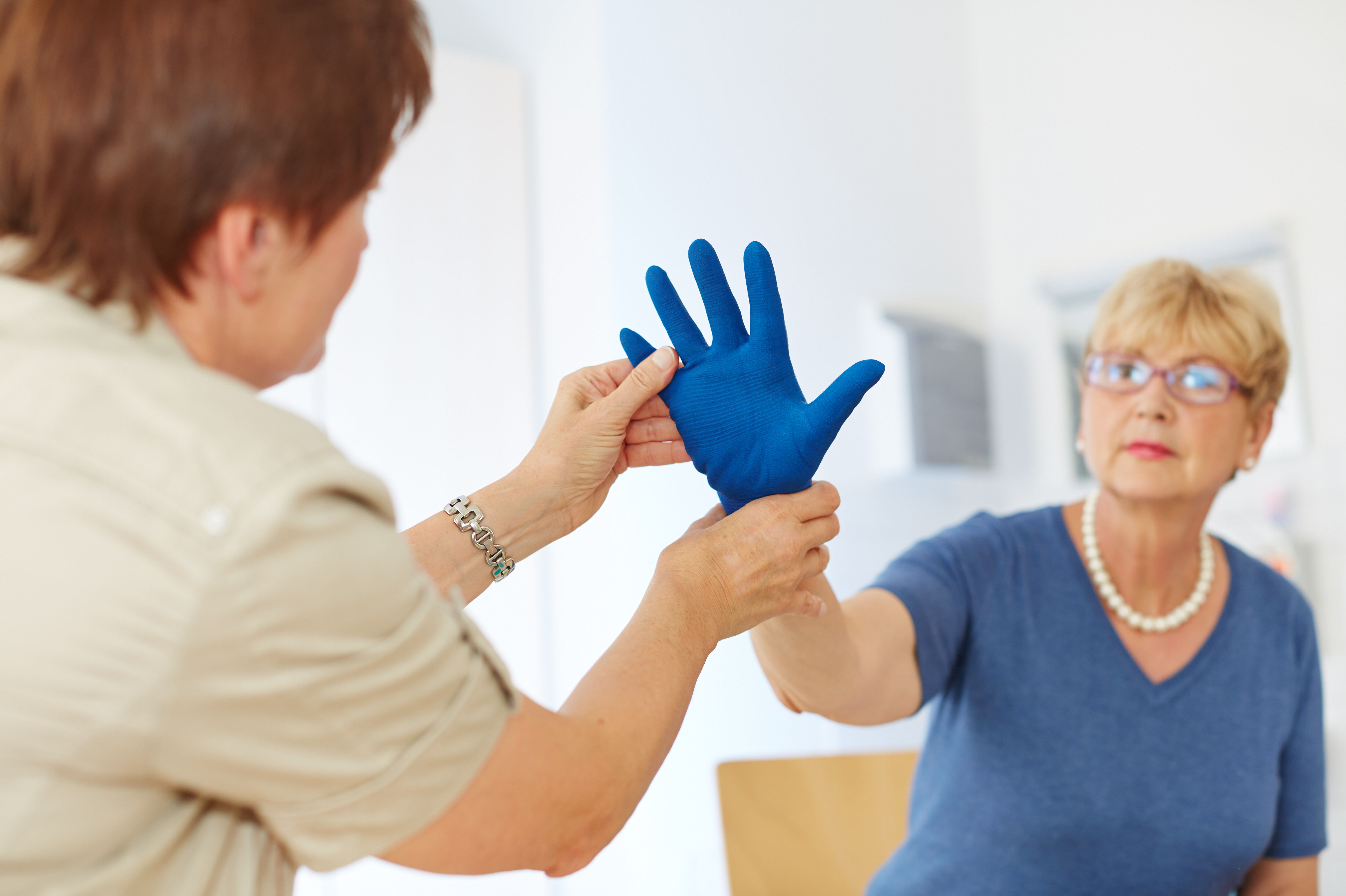 Eine Therapeutin berät eine Patienten zum Thema Handschuhe