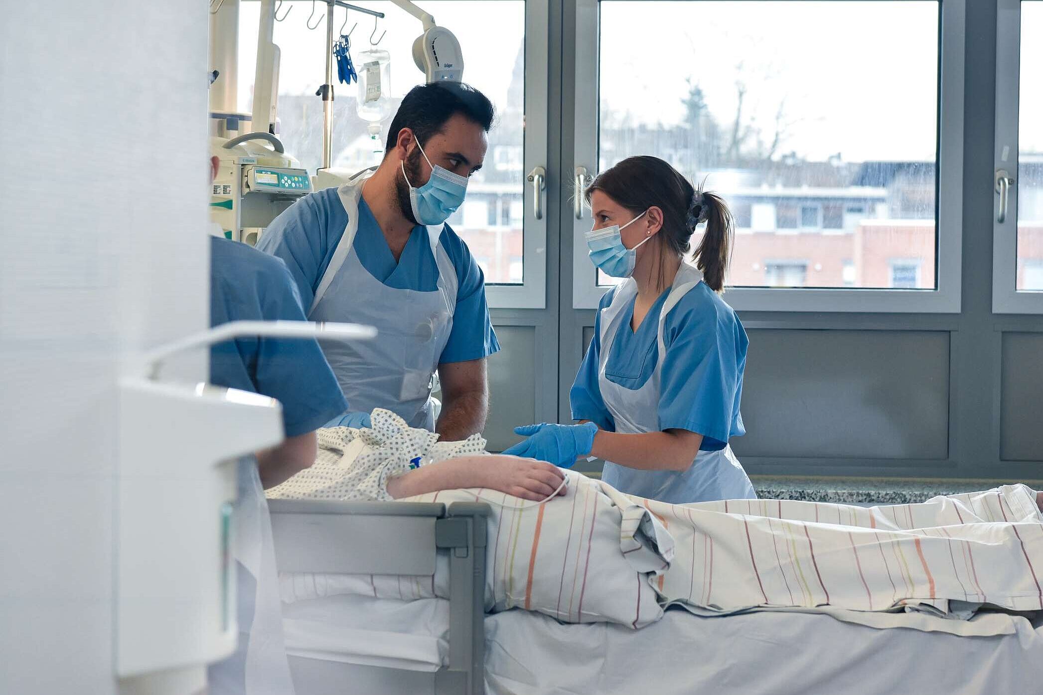 Zwei Pflegefachkräfte am Bett eines Patienten auf der Intensivstation