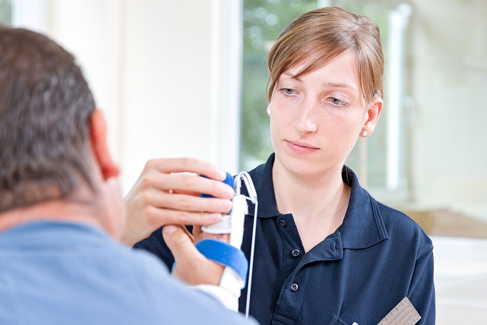 Therapeutin behandelt Patienten mit einer Handverletzung 