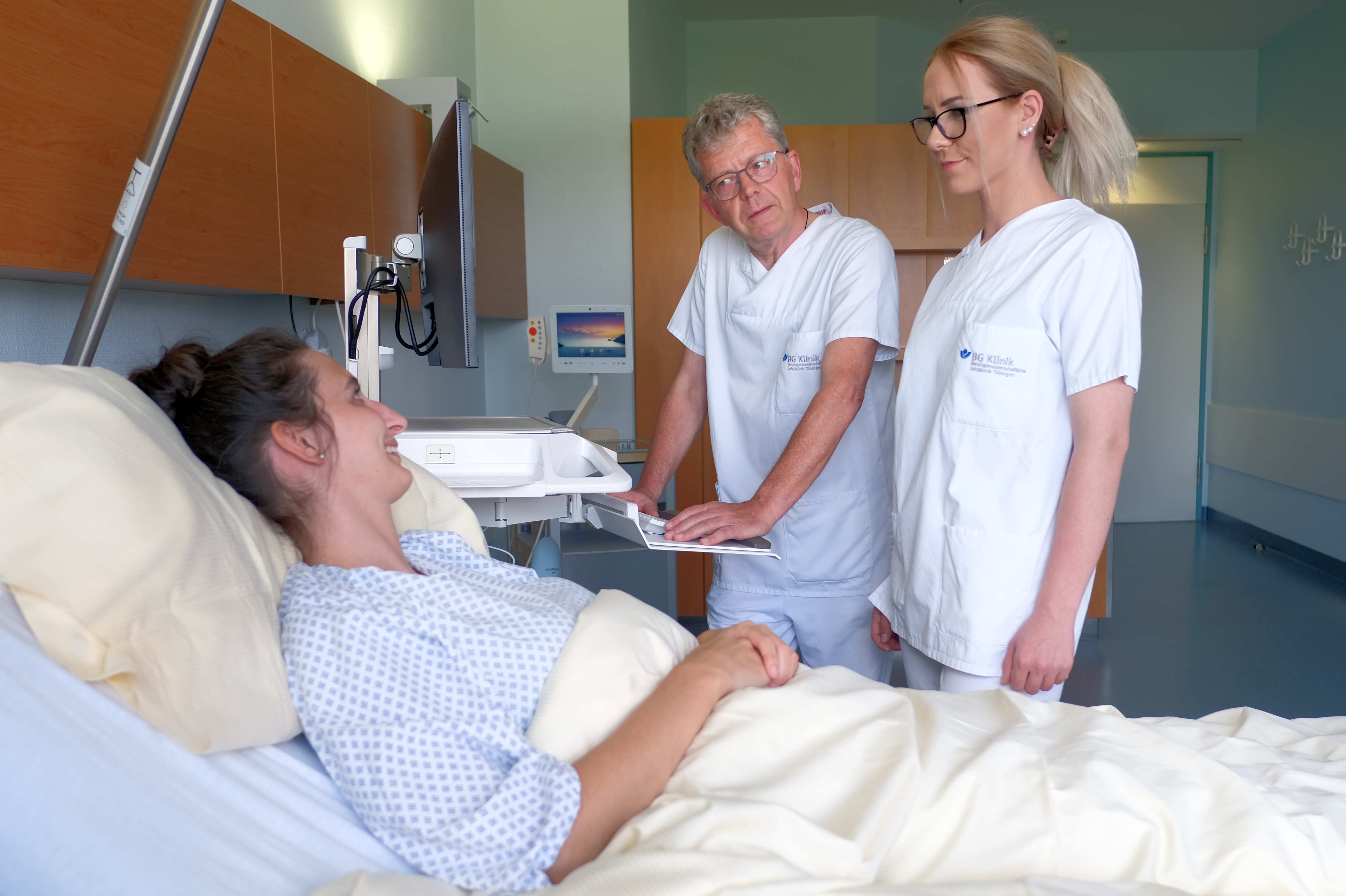 Zwei Pflegekräfte am Patientenbett im Gespräch.