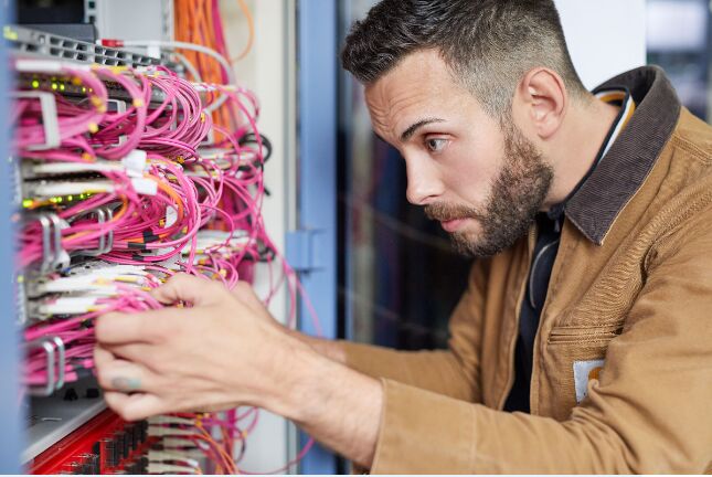 Einsatz im Rechenzentrum: Fabian Tarruhn patcht einen Switch im Verteilerschrank. Ein neu eingerichteter Raum in der Rettungsstelle des ukb hat jetzt Netzwerkanschluss.