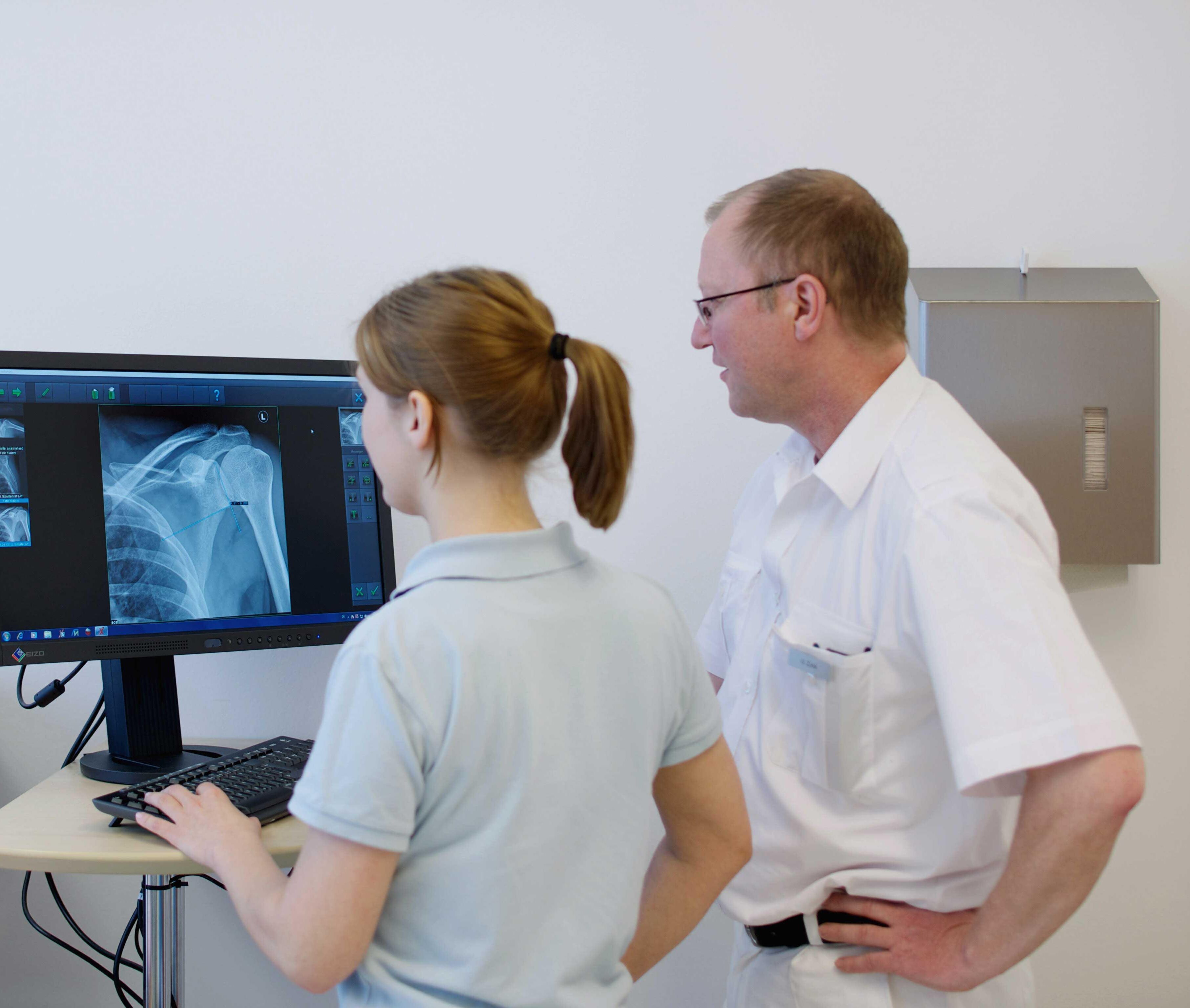 Unfallchirurg und MFA betrachten Röntgenbild