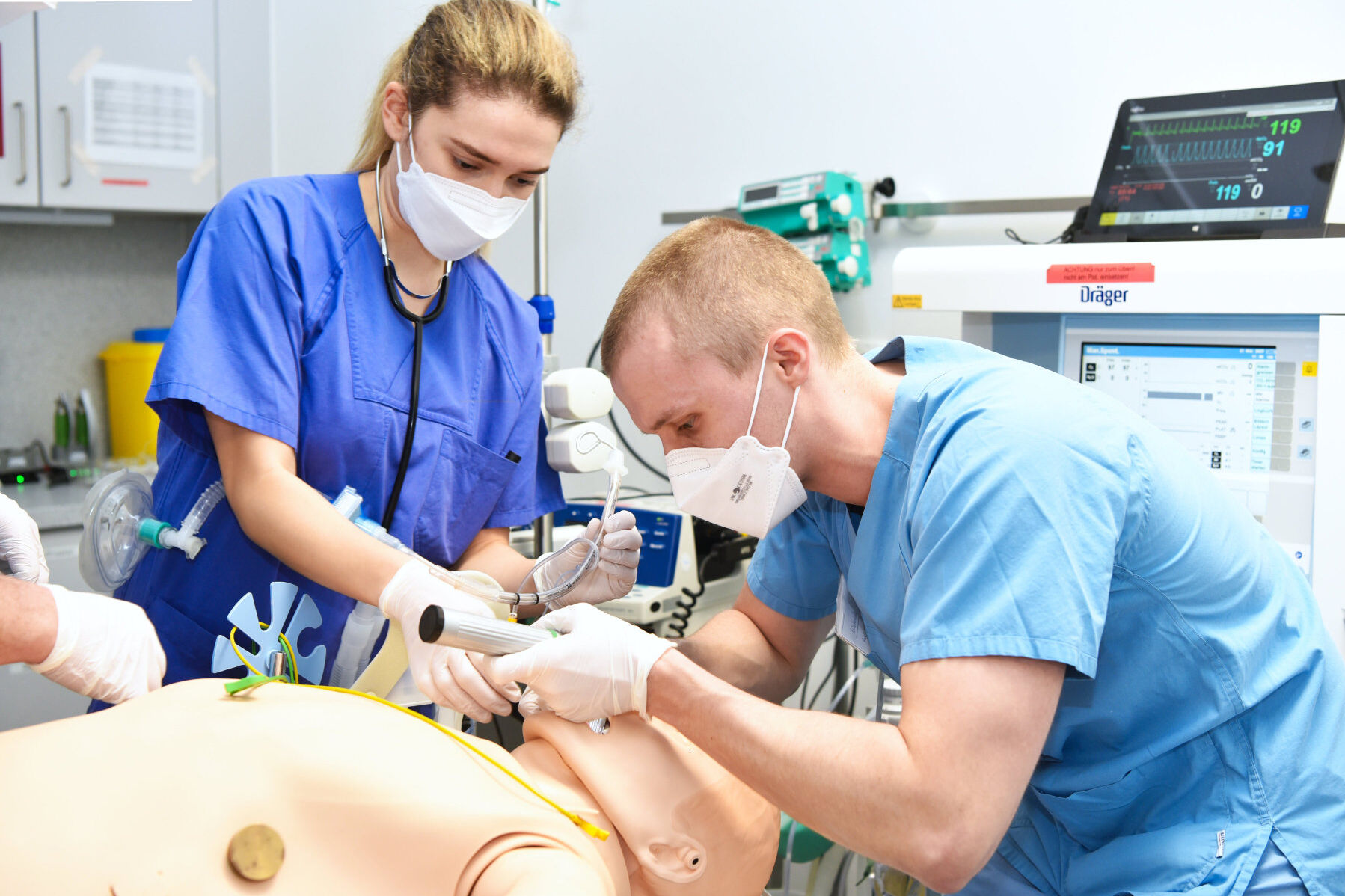 Die Mitarbeitenden trainieren, den Patienten-Dummy mit einem Schlauch über die Luftröhre zu beatmen. Bildnachweis: BG Universitätsklinikum Bergmannsheil