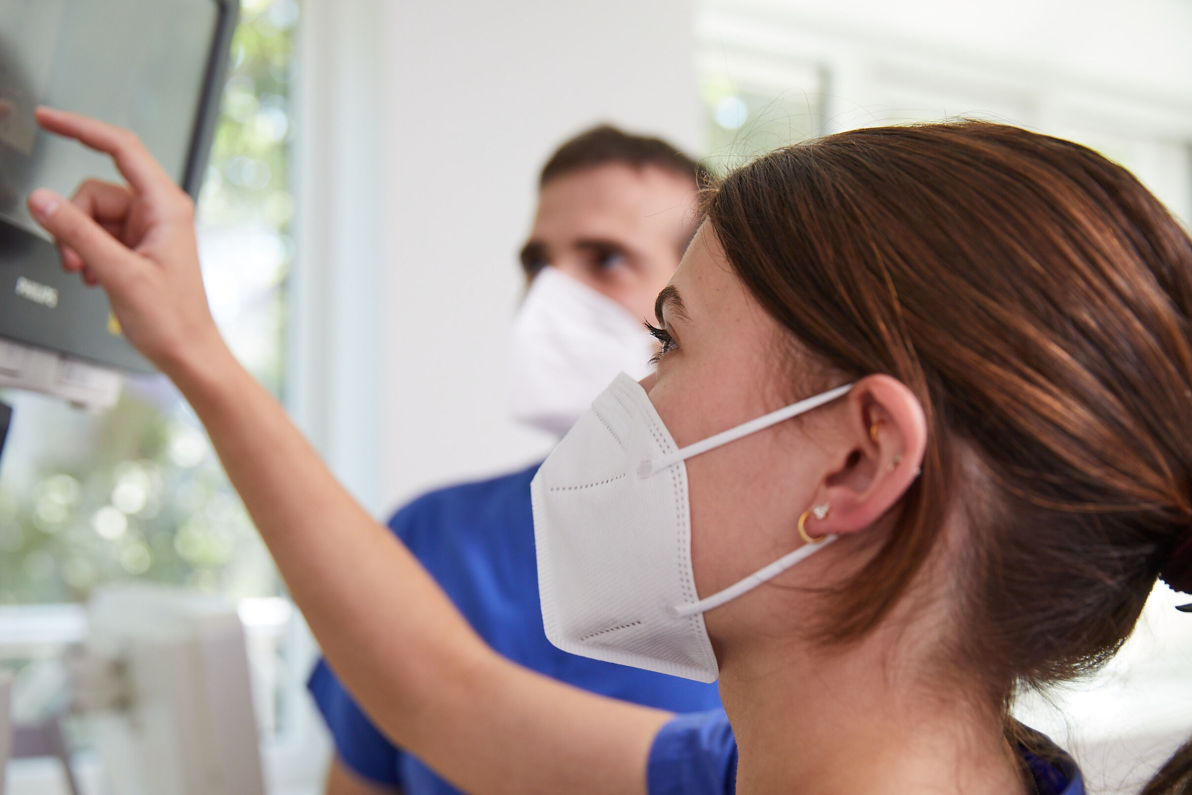 Applikationsmanagement Frau mit Maske zeigt auf Monitor