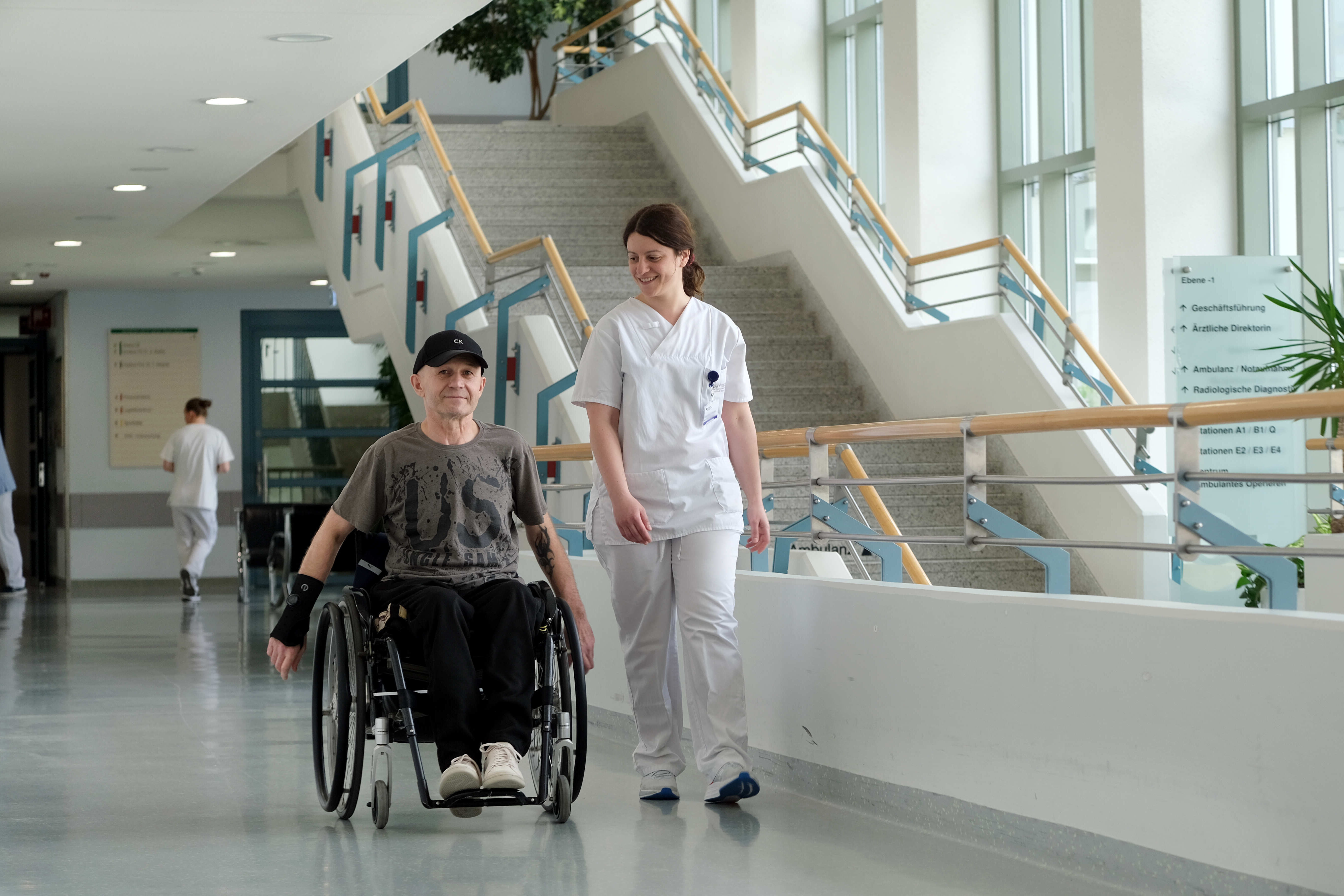 Patient im Rollstuhl mit Pflegefachkraft